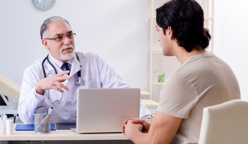 Pacient bărbat care discută cu un medic în cabinet despre cele mai frecvente boli la bărbați
