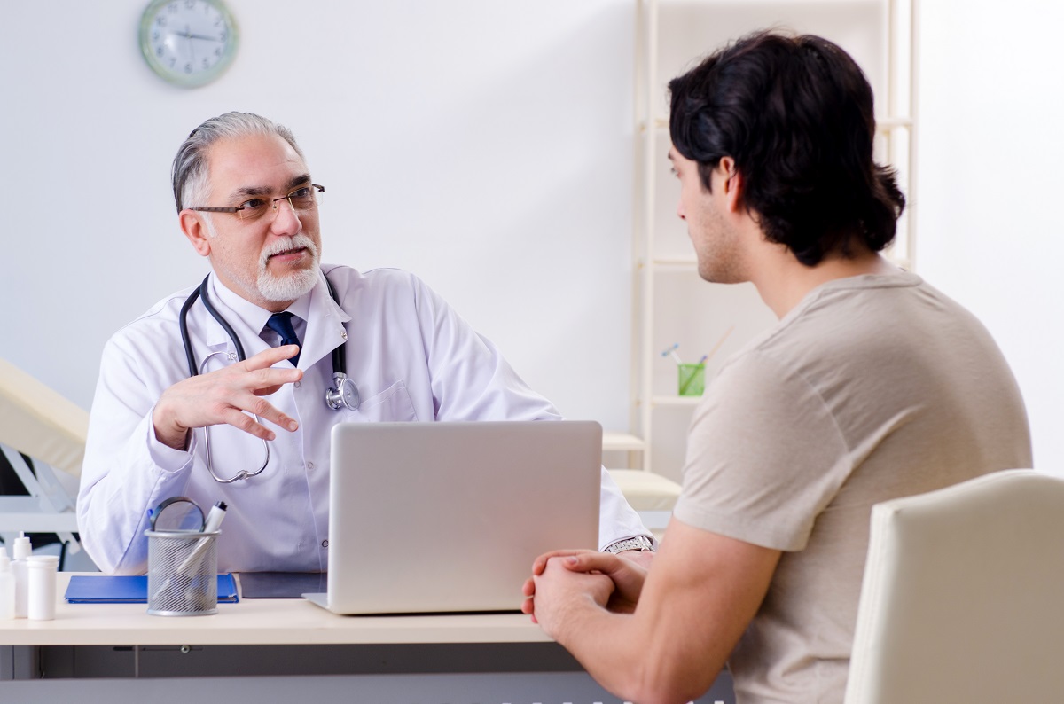 Pacient bărbat care discută cu un medic în cabinet despre cele mai frecvente boli la bărbați