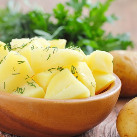 Un castron cu: cartofi fierți, mărar și ulei, înconjurat de legume