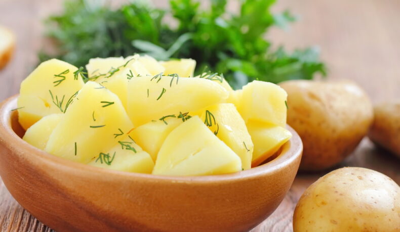 Un castron cu: cartofi fierți, mărar și ulei, înconjurat de legume
