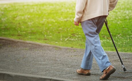 Bătrân care merge în baston în parc, sugestiv pentru problemele de mers care apar în boala Alzheimer