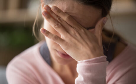 O femeie tânără își ține o mână pe față din cauza unei dureri