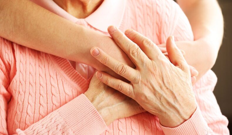 Detaliu cu îmbrățișarea unei femei în vârstă și mâini împreunate