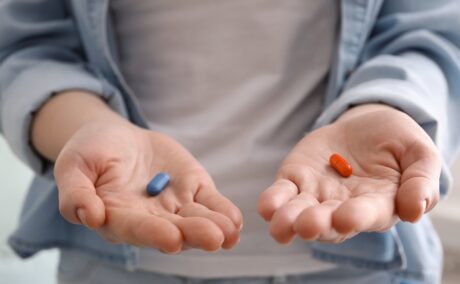 Femeie cu câte o pastilă în fiecare palmă, sugestiv pentru recomandarea de a admiistra magneziul și vitamina D împreună