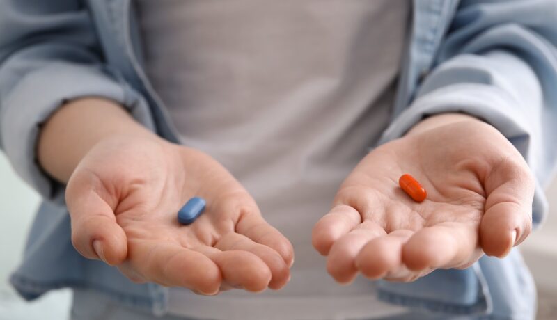 Femeie cu câte o pastilă în fiecare palmă, sugestiv pentru recomandarea de a admiistra magneziul și vitamina D împreună
