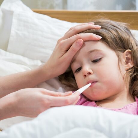 Fetiță bolnavă cu febră și cu termometru în gură, febra fiind unul dintre simptomele infecției cu virusul sincițial respirator