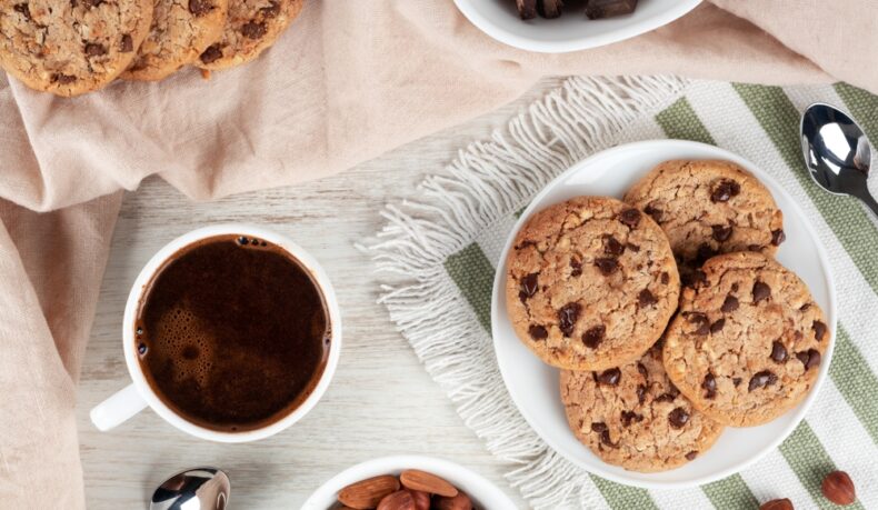 Castroane cu: biscuiți, ciocolată și migdale, lângă o ceașcă cu cafea și linguri