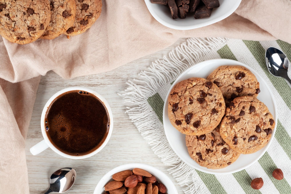 Castroane cu: biscuiți, ciocolată și migdale, lângă o ceașcă cu cafea și linguri