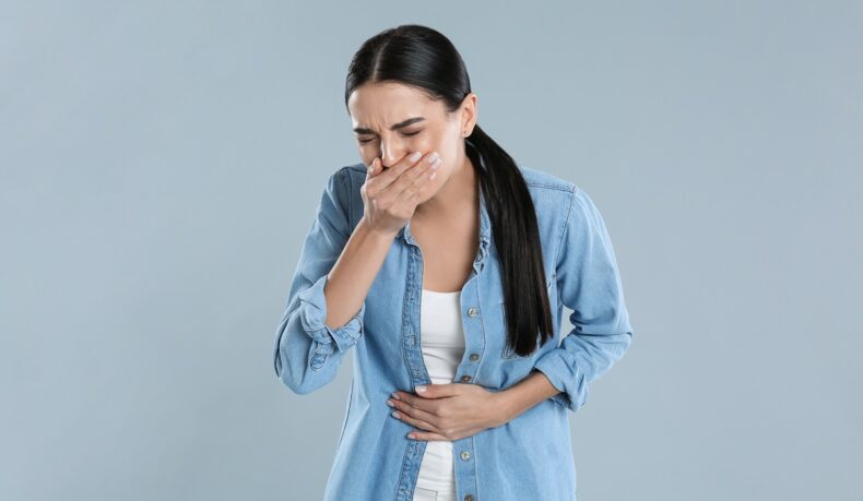 Femeie cu durere de burtă și stare de greață, sugestiv pentru indigestie alimentară