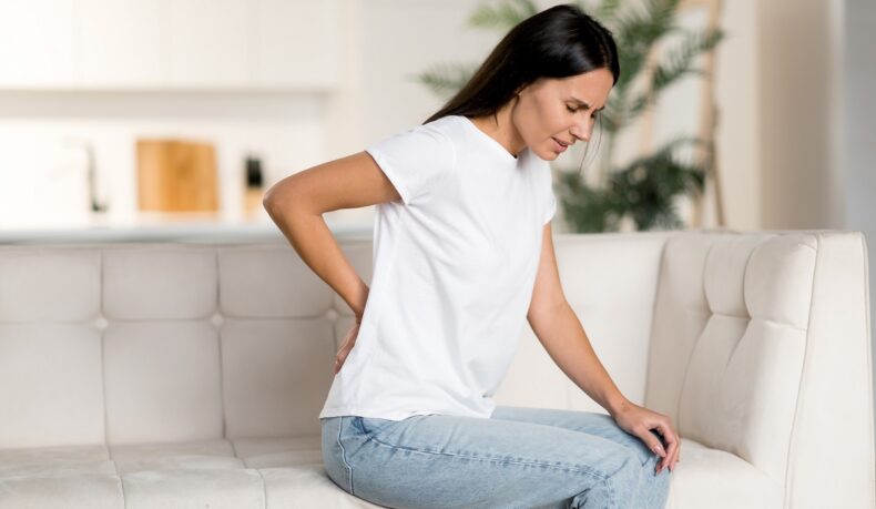 Femeie pe canapea cu durere lombară sau lumbago