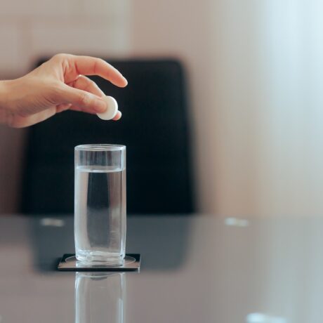 Detaliu cu mână care pune o pastilă efervescentă într-un pahar cu apă, care poate fi un supliment cu magneziu pentru anxietate