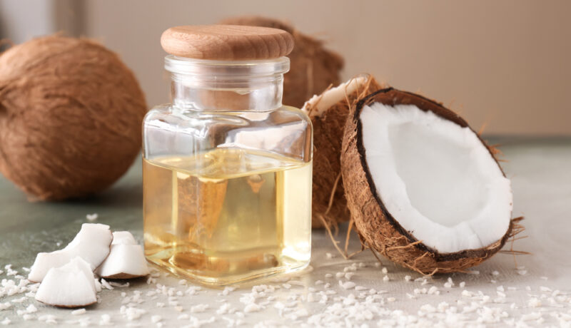 Un borcan cu ulei de cocos, lângă nuci de cocos