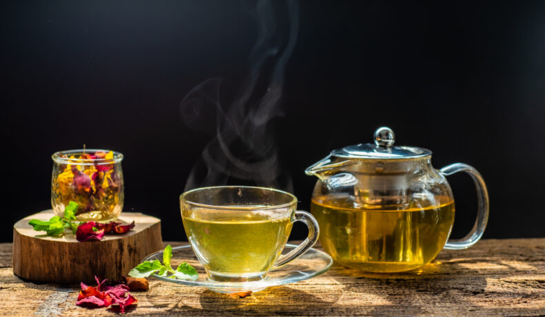 O cană cu ceai, lângă un vas cu ceai și un borcan cu flori uscate