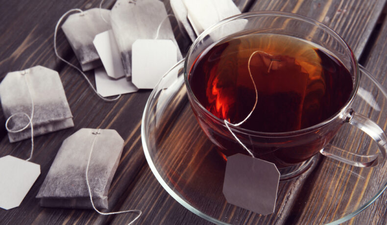 O cană cu ceai lângă pliculețe de ceai