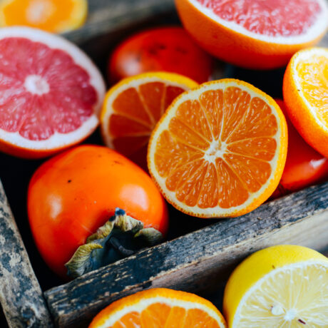 Felii de: lămâi, portocale și grepfrut, amestecate într-o cutie cu kaki