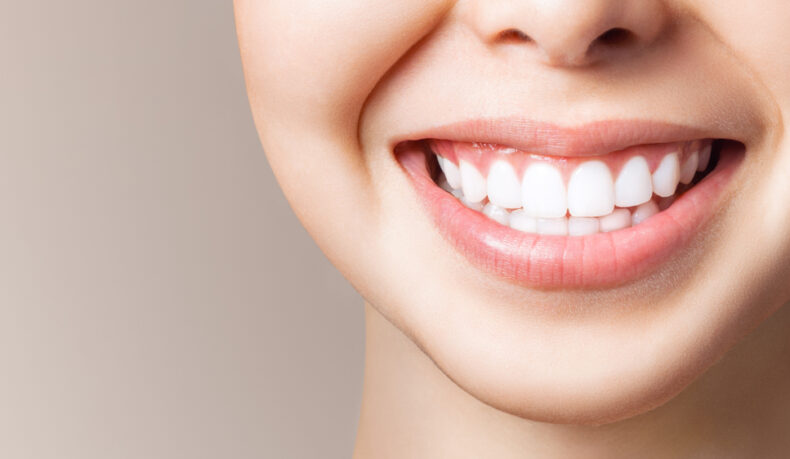 O femeie tânără zâmbește și își arată dinții albi