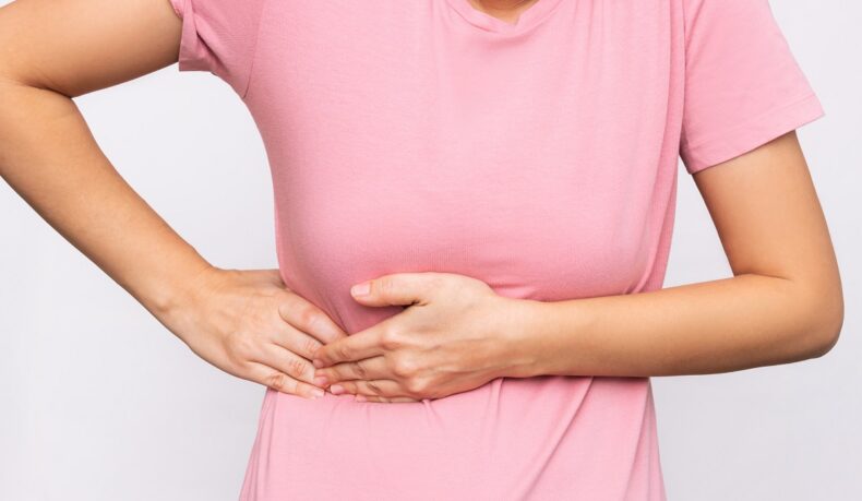Femeie cu mâinile în partea dreaptă a abdomenului, sugestiv pentru durerea de vezică biliară sau crizele de fiere