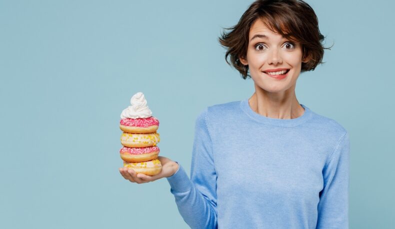 Femeie cu gogoși în mână, sugestiv pentru întrebarea: poți face diabet de la dulciuri?