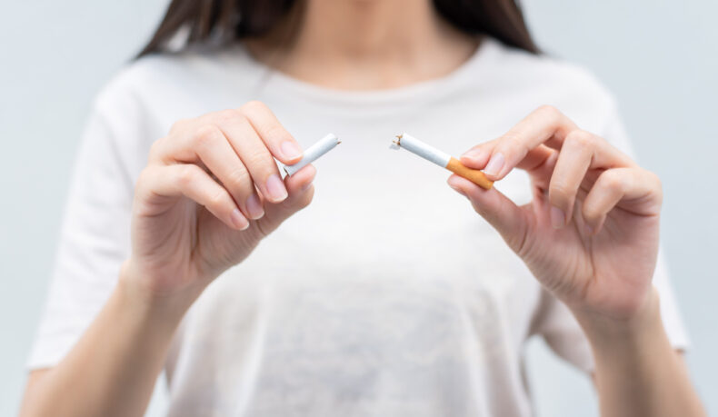 O femeie tânără ține două jumătăți de țigară
