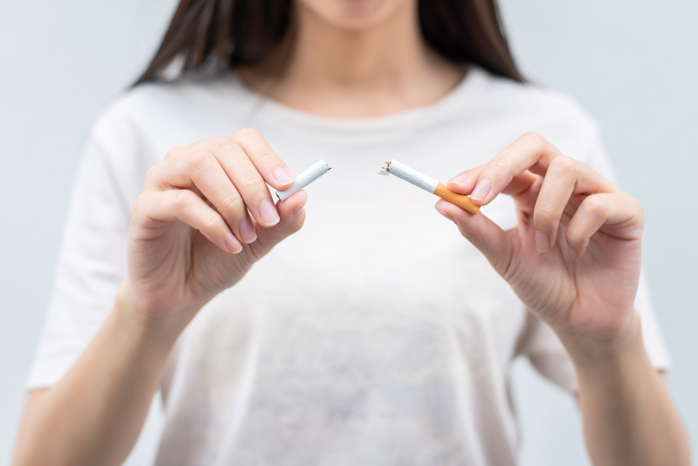 O femeie tânără ține două jumătăți de țigară