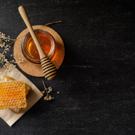 Un borcan cu miere lângă faguri de miere