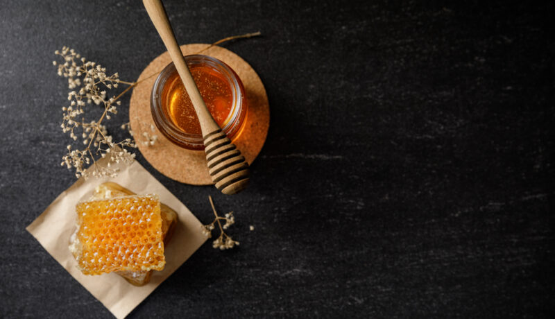 Un borcan cu miere lângă faguri de miere