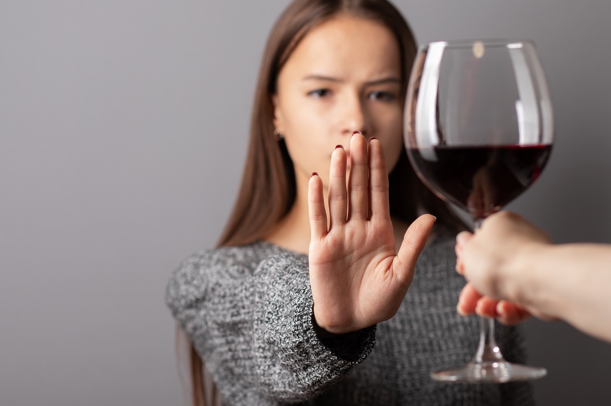 Femeie care face un semn de refuz cu mâna către un pahar de vin