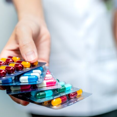 Femeie care ține în mână mai multe folii cu antibiotice diferite, sugestiv pentru rezistența la antibiotice