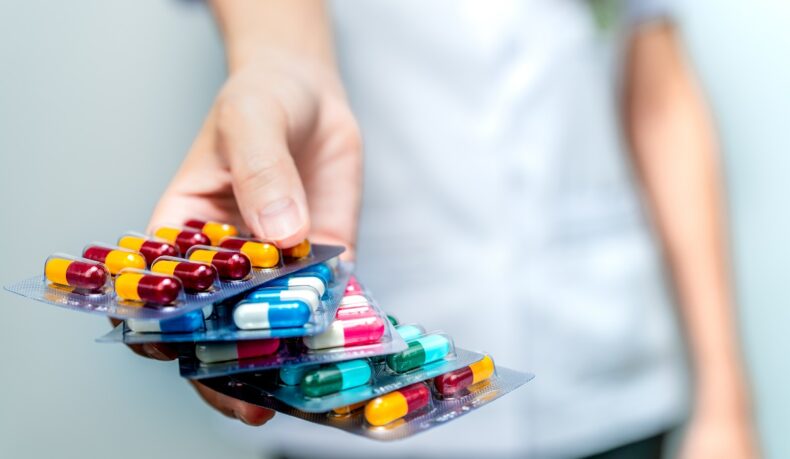 Femeie care ține în mână mai multe folii cu antibiotice diferite, sugestiv pentru rezistența la antibiotice