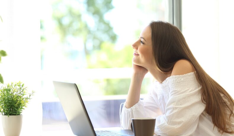 Femeie în fața laptopului care visează cu ochii deschiși, obiceiul care ajută memoria