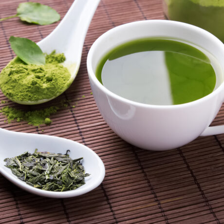 O ceașcă cu ceai verde, lângă linguri cu extracte din plante
