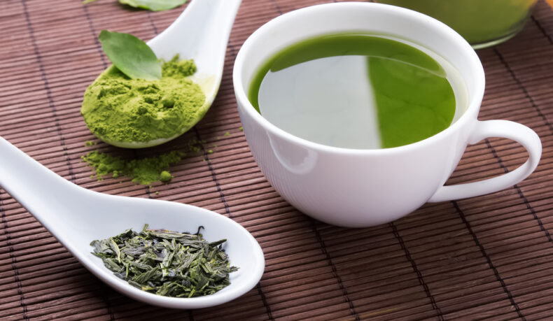 O ceașcă cu ceai verde, lângă linguri cu extracte din plante