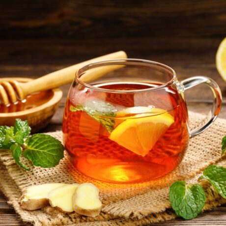 O ceașcă cu ceai de lămâie pe un șervet, lângă un castron cu miere și o felie de lămâie