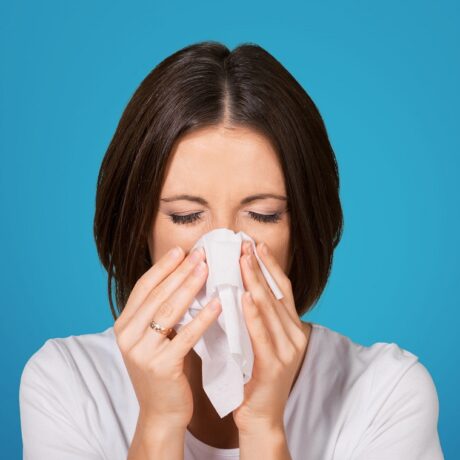 Femeie care își suflă nasul, unul dintre simptomele specifice pentru polipii nazali