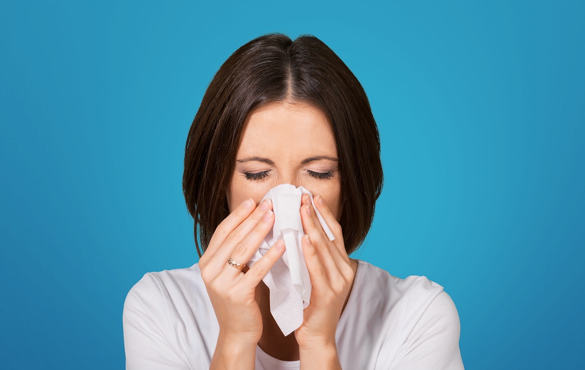 Femeie care își suflă nasul, unul dintre simptomele specifice pentru polipii nazali