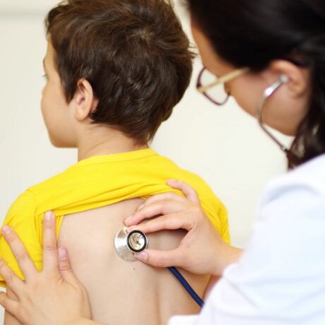 Medic care ascultă cu stetoscopul spatele unui băiețel, sugestiv pentru wheezingul la copii