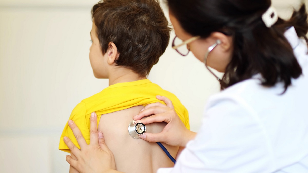 Medic care ascultă cu stetoscopul spatele unui băiețel, sugestiv pentru wheezingul la copii