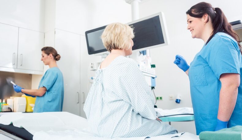Medic în sala de intervenții care discută cu o pacientă despre pregătirea pentru colonoscopie