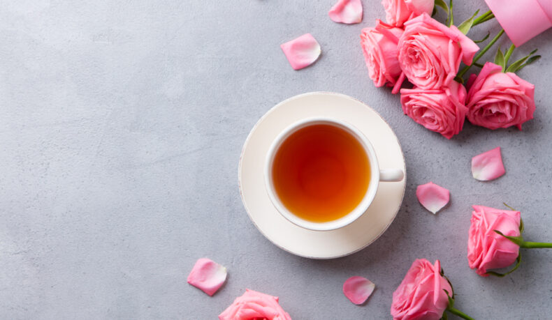O ceașcă cu ceai de trandafiri, lângă un buchet de trandafiri