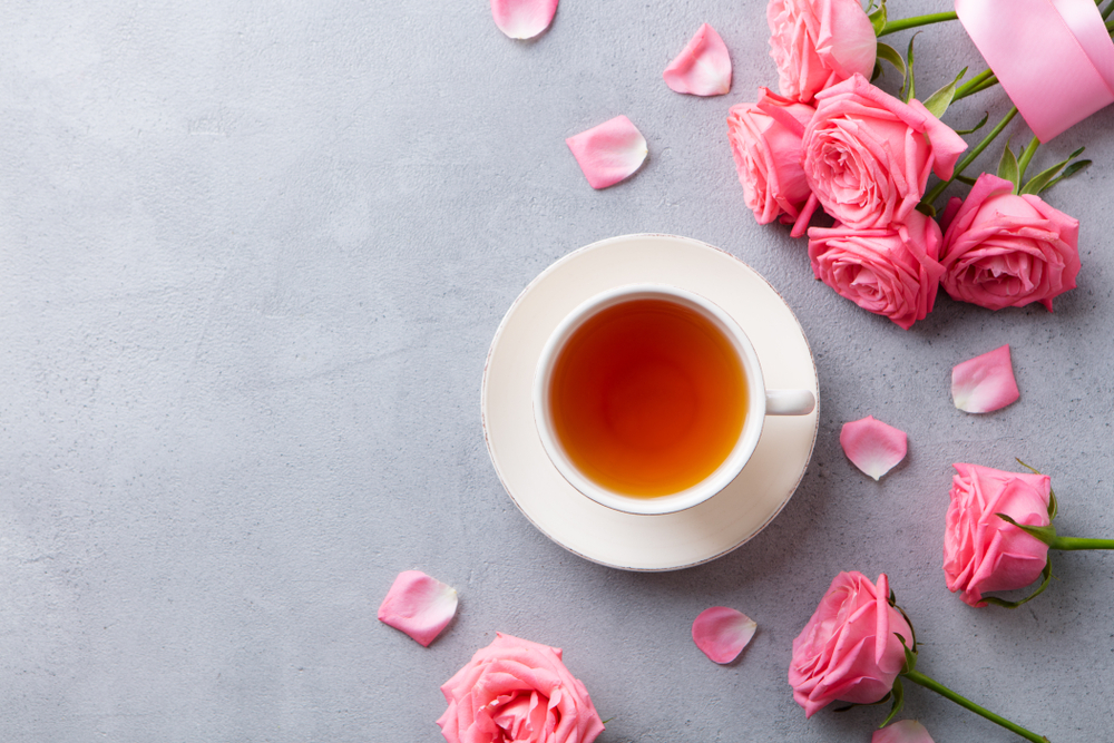 O ceașcă cu ceai de trandafiri, lângă un buchet de trandafiri