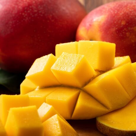 Mango tăiat și mango întreg pe un blat din bucătărie