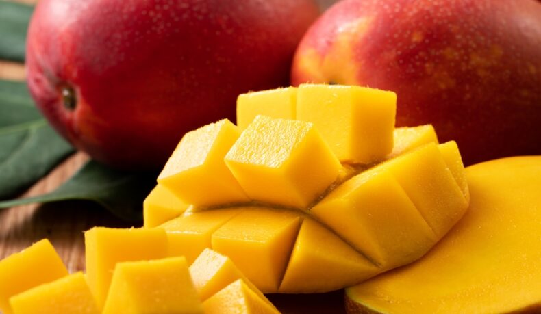 Mango tăiat și mango întreg pe un blat din bucătărie