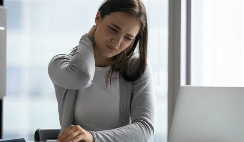 Femeie la birou cu durere de gât, unul dintre efectele sedentarismului