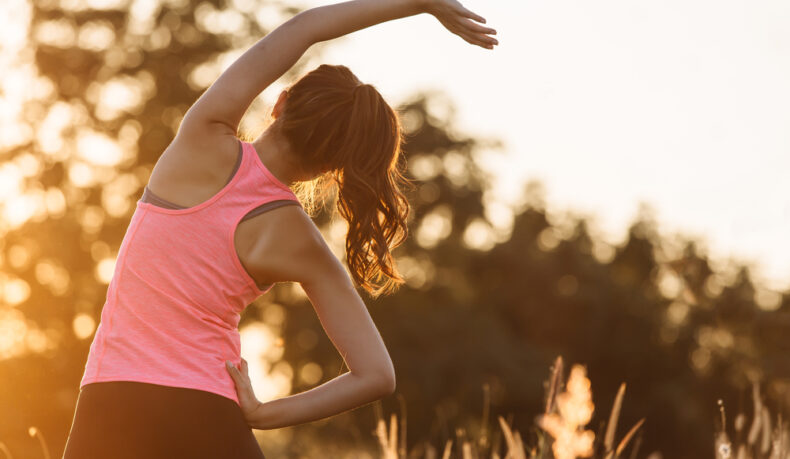 O femeie tânără face exerciții de stretching în natură