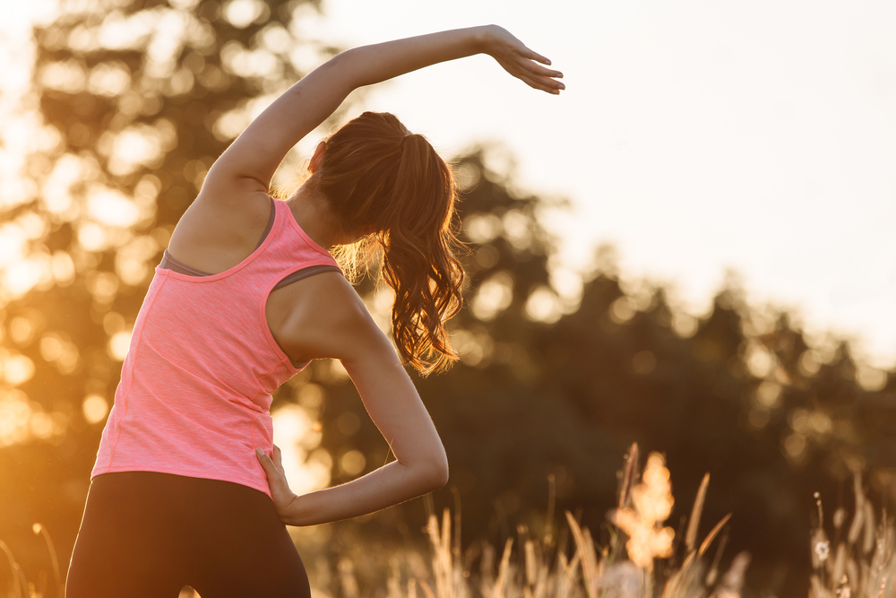 O femeie tânără face exerciții de stretching în natură