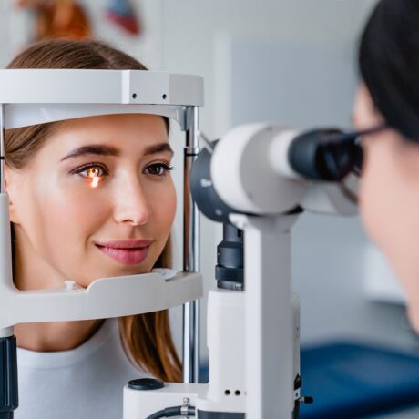 Oftalmolog care consultă o pacientă la un aparat de optometrie folosit în diagnosticul unor afecțiuni ale ochiului