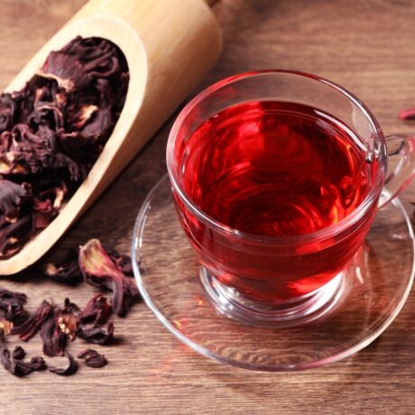 O ceașcă cu ceai de hibiscus și o lingură cu petale uscate