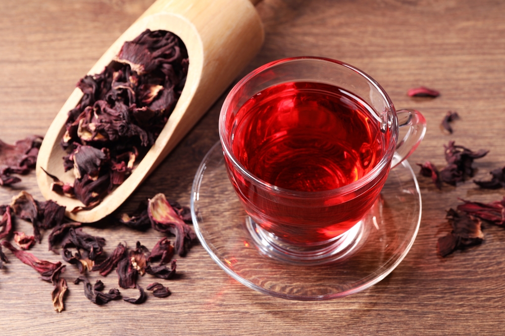 O ceașcă cu ceai de hibiscus și o lingură cu petale uscate