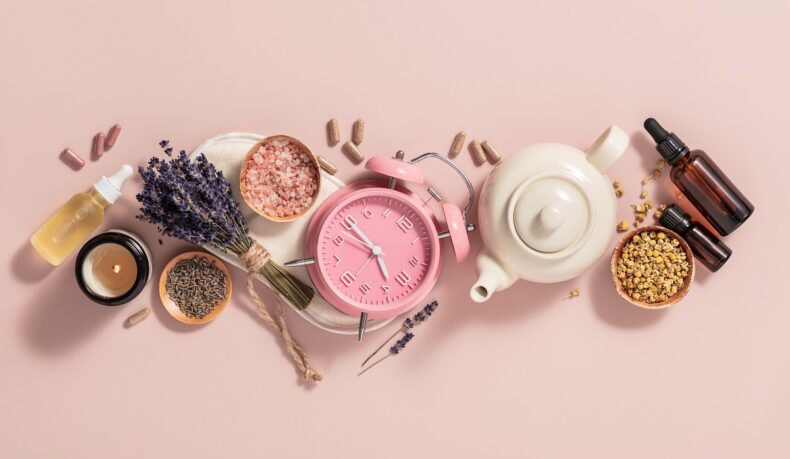 ceas roz, ceai, lavandă, uleiuri esențiale și alte remedii pentru insomnie pe fundal roz