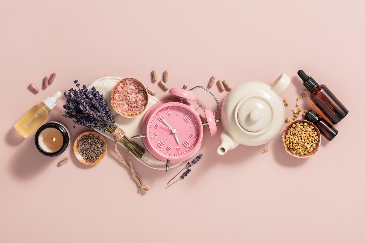 ceas roz, ceai, lavandă, uleiuri esențiale și alte remedii pentru insomnie pe fundal roz